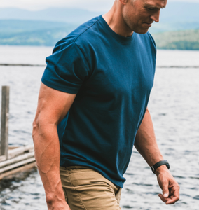 Man wearing a blue t-shirt and beige pants by a lake nav CTA